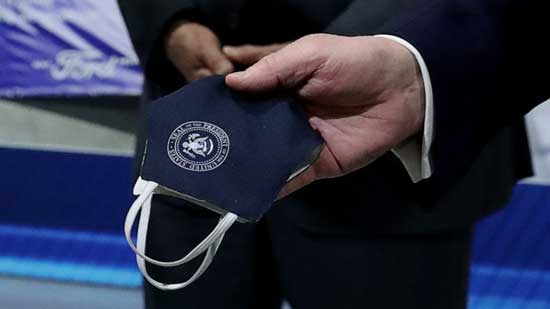 President Donald Trump holds a protective face mask with a presidential seal on it that he said he had been wearing earlier in his tour at the Ford Rawsonville Components Plant in Ypsilanti, Mich., May 21, 2020.President Donald Trump holds a protective face mask with a presidential seal on it that he said he had been wearing earlier in his tour at the Ford Rawsonville Components Plant in Ypsilanti, Mich., May 21, 2020. Leah Millis/Reuters, FILE